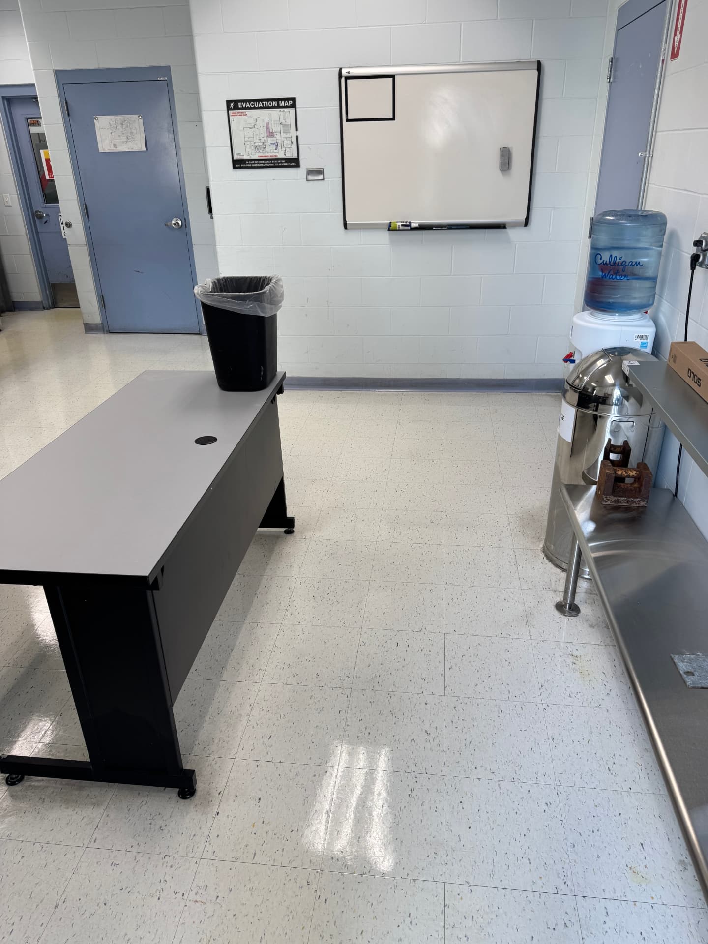 Glossy cleaned floor in a facility workroom with a whiteboard and water cooler