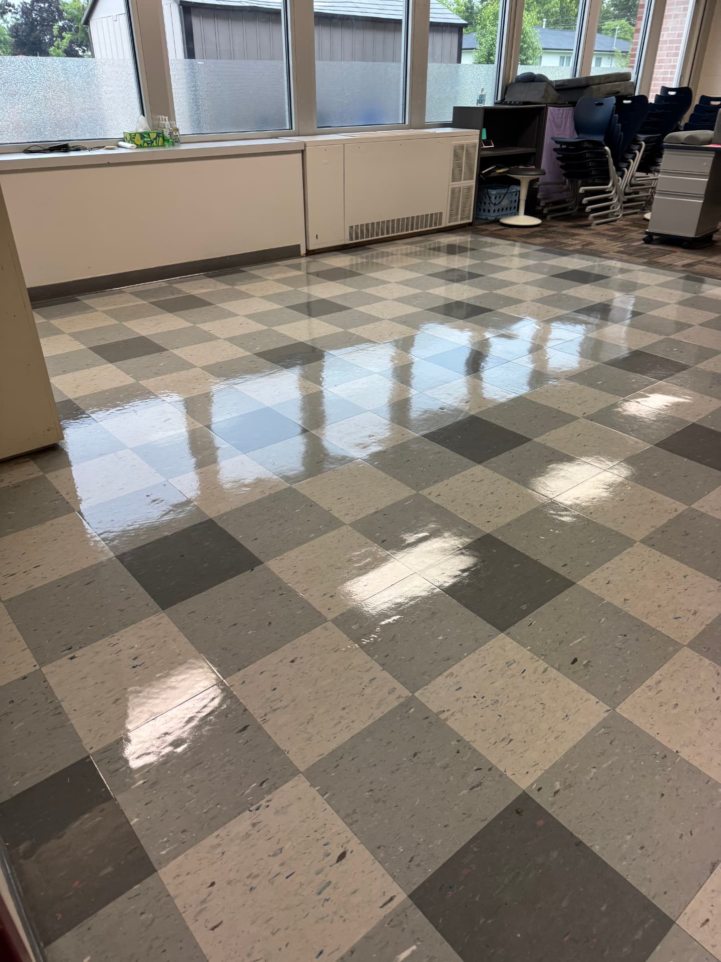 Freshly stripped and waxed checkered tile floor in a school classroom with stacked chairs